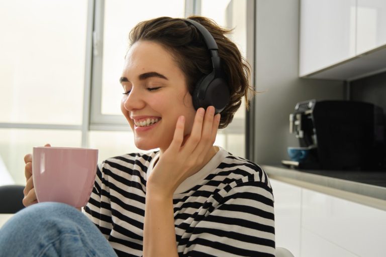 Una mujer joven relajada escuchando su playlist favorita con audífonos inalámbricos por la mañana.