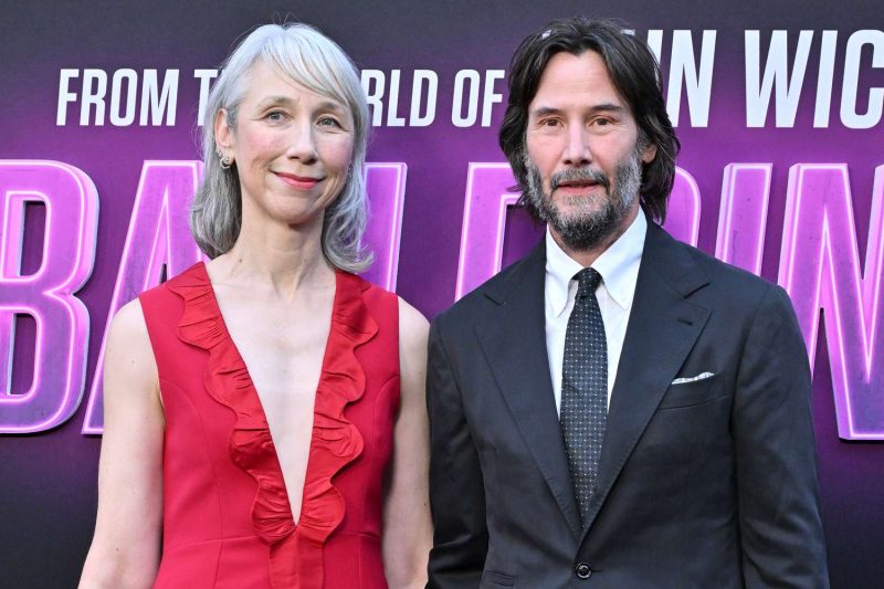Una fotografía de Alexandra Grant y Keanu Reeves posando en una alfombra roja.